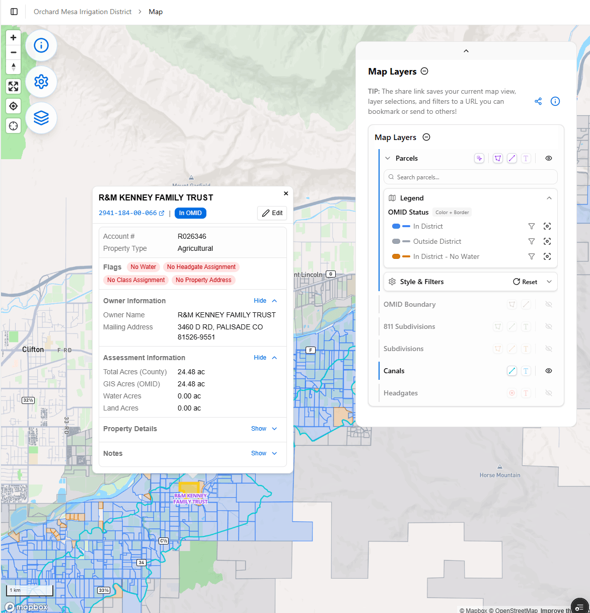 Interactive Parcels Map (OMID). A layered map of the district's parcels with a right-hand Map Layers panel - Parcels with an OMID Status legend, In-Canal / In-District filter toggles, Style & Filters, plus OMID Boundary, RTI Subdivisions, Subdivisions, Canals and Headgates layers. Clicking a parcel opens a detail card (e.g. R&M Kenney Family Trust) showing Account #, Property Type, status flags, Owner Information, Mailing Address, Assessment Information (Total/OMID/Water/Land Acres), Property Details and Notes. Demonstrates an interactive, multi-layer parcel map with click-through records tied to the assessment data.